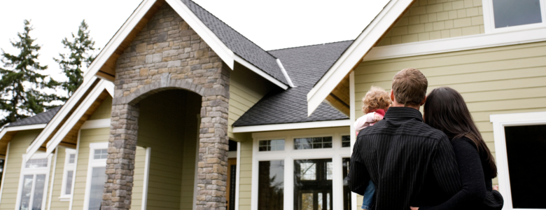 Young family standing in the front yard with home in the background
