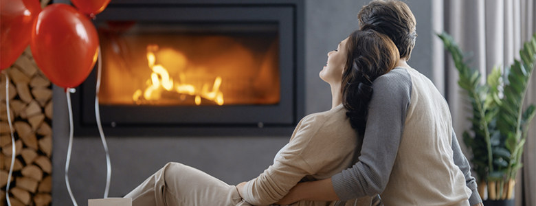 Couple in front of a fireplace with red balloons