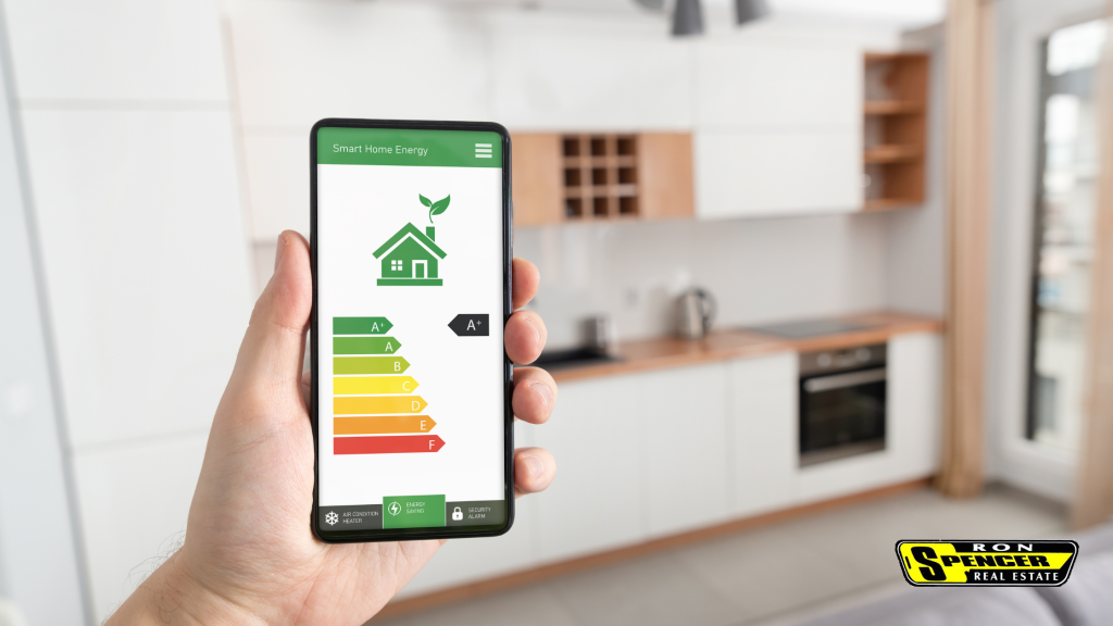 A hand holding a smartphone with an energy efficient grading system for a home shown on it holding it up in front of a kitchen counter area 