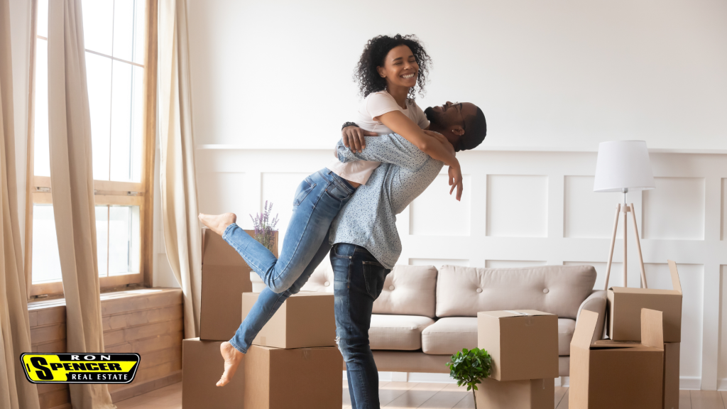 man and woman embracing and looking excited for their new home surrounded by moving boxes