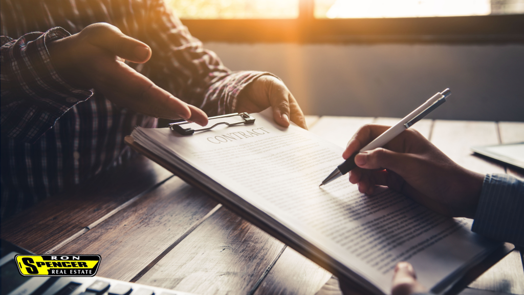 Person sitting at a desk with contract papwerwork ready to sign for a real estate purchase